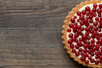 rote Johannisbeeren und Pudding in Törtchen auf Tisch aus Holz