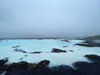 Back rocks and blue water in Iceland near the Blue Lagoon in the fog