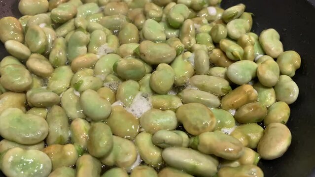 (Slow-Motion) Close up shot cooking broad beans in a pan.