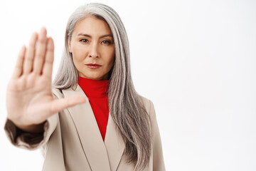 Close up portrait of senior asian businesswoman, japanese corporate lady showing stop, prohibit, rejection gesture, saying no with serious face, white background - 521081158
