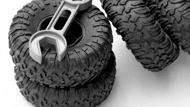car repair and maintenance,tires replacement. rubber black tires from toy car grey little plastic wrench spinning on gray background.save money,service costs concept 4k real time video
