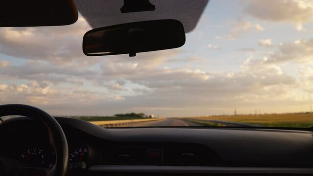 View From The Front Window Of A Car Driving Along The Highway At Sunset And A Beautiful Cloudy Sky. No People. Go Everywhere. Concept Of Travel By Vehicle.