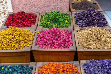 Many different colourful spices in squared wooden boxes in a spices market