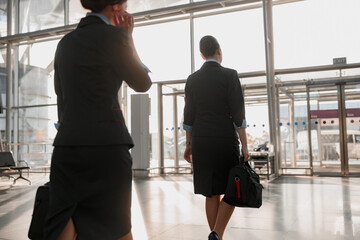 Two stewardesses walking to the airport terminal exit
