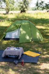 modern green camping tent with outdoor frame set up in the forest
