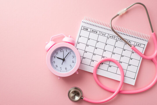 Breast cancer awareness concept. Top view photo of calendar pink alarm clock and stethoscope on isolated pastel pink background