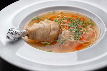 Chicken broth with noodles and chicken leg. With selective focus
