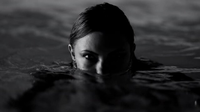 Charming woman swimming in pool water under neon color light. Party, attractive girl in shining dress enjoying night time. Work as model or actress, influencer