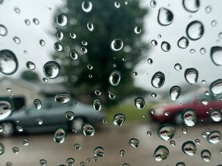 cars parked on a street through rain drops on a gray rainy day
