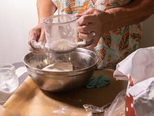 an elderly woman sifts flour to make dough for homemade pies