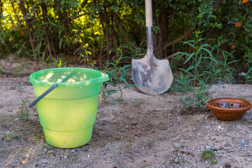 bucket with water and metal shovel on the ground