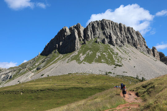 people walking along the mountain path towards the mountain called CASTELLAZ in Italy