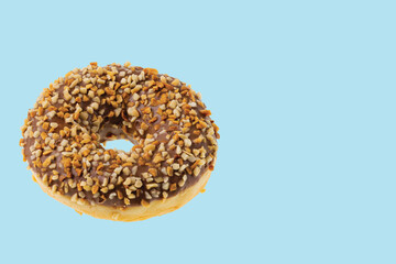 Close up view of chocolate donut sprinkled with nuts isolated on blue background.  Sweden.
