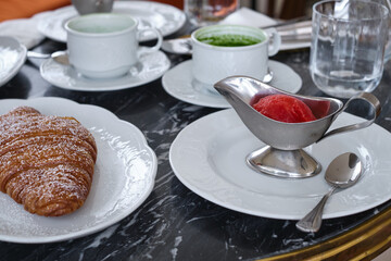 Crispy croissant on a white plate on a table in a cafe. Fresh homemade cakes. Delicious traditional french crispy croissants for breakfast
