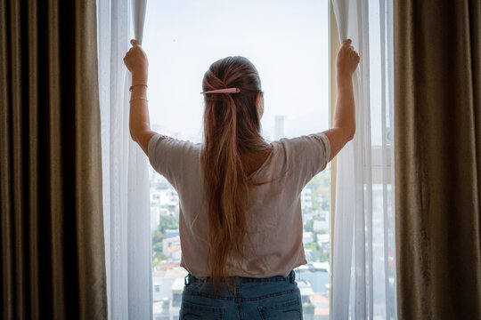 Mujer abriendo la ventana de su habitaci&oacute;n para que entre luz natural