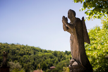 Statue of a praying angel outside Santa Maria and San Giorgio church in Fortunago, one of the most charming villages of Oltrep&ograve; Pavese, Lombardia countryside, Italy. Background with copy space.