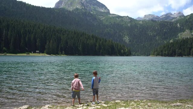 Zabljak, Montenegro - 05.08.20: Children throw pebbles into the Black Lake water in Durmitor National Park