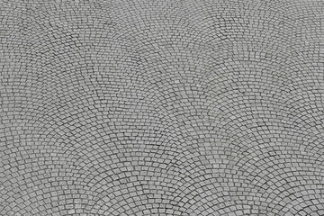 Grey cobblestone urban sidewalk paving with granite rock top view. Square of historical town place...