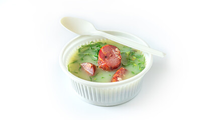 Portuguese green soup to go called Caldo Verde with chorizo sausage. Take away food in eco container on a white background