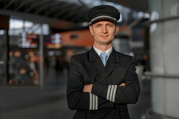 Smiling adult pilot in hat posing at camera in terminal © Friends Stock