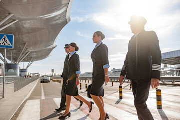 Flight attendants and pilots walking in a row and crossing the road