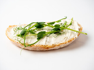 Close-up of a slice of bread spread with cottage cheese and decorated with micro greenery isolated on a white background. The concept of proper nutrition. Healthy snack, diet