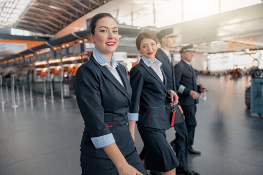 Two flight attendants and pilots walking through the terminal to the plane
