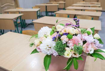 A bouquet of flowers stands on a table in the classroom. Greeting card with the beginning of the...