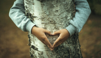 The hands of a child in the form of a heart on a tree trunk. Love in the family. Show the heart...