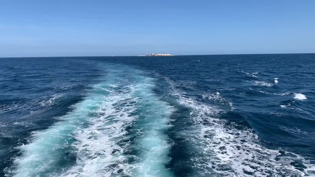 (Slow Motion) Sailing through the Mediterranean Sea with the Island of Tabarca in the background, located on the coast of Alicante, in the Valencia Community, Spain.