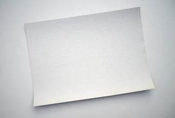 A white cardboard sheet of paper on a white table. A blank sheet for the text. White background for the ad label.