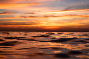 Naklejka na ściany i meble beautiful sea sunset, the wave closes the sun. View very close to the water