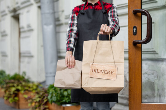 woman holds a wooden sign with the inscription takeaway, open or closed at the door of a restaurant or coffee shop. the working hours of the restaurant or the food and beverage delivery service. to