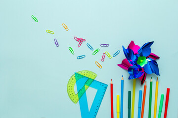 Back to school. Pinwheels, pencils, ruler, paper clips on a blue background. Knowledge Day. Background with a place for an inscription