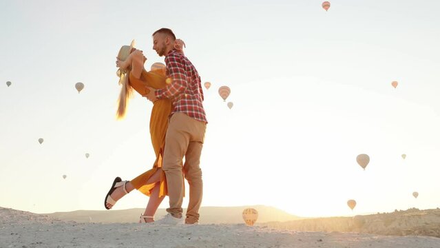 Happy couple kissing against the backdrop of air layers on Goreme Hill, Cappadocia, Turkey. Cappadocia is one of the best places for hot air ballooning.