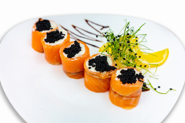Rolls of sushi from red fish with black caviar on a white plate