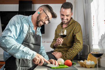Happy gay couple in love standing in the kitchen. They are cooking dinner together at home. High quality photography