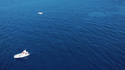 Two small white private boats on a dark-blue waters of a calm sea. Aerial view. No sky, just the sea. High quality photo