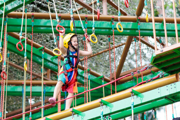 Child in adventure park. Kids climbing rope trail.