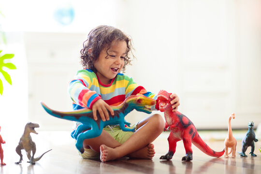 Child playing with toy dinosaurs. Kids toys.