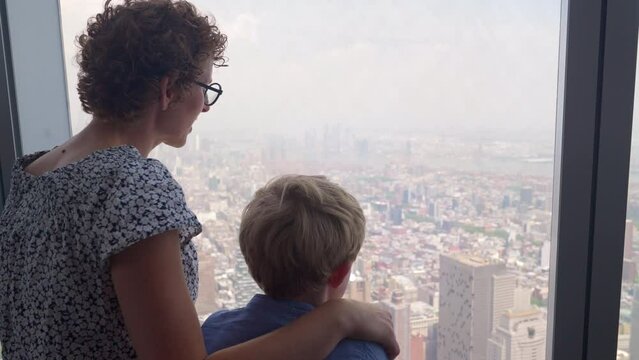 Mother And Son Looking Through Skyscraper Window To New York City