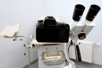 a modern microscope connected to a reflex camera against the background of a medical chair