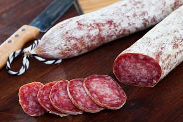 Catalan sort of popular Spanish Longaniza sausage from minced pork with cut slices on wooden surface..