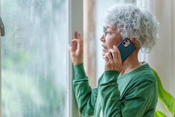 大雨の中電話をかけるシニア女性