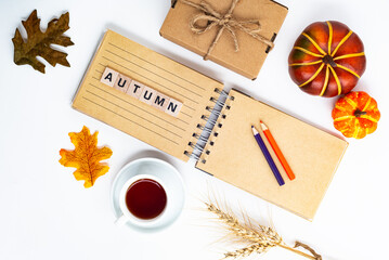 Autumn composition: fallen leaves and a notepad. space for text. the word AUTUMN is composed of wooden cubes.