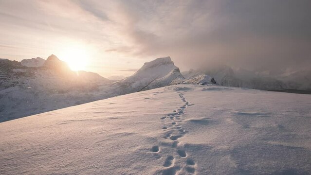 Sunrise over snowy mountain peak with footprint on winter in the morning at Segla mount, Senja island, Norway