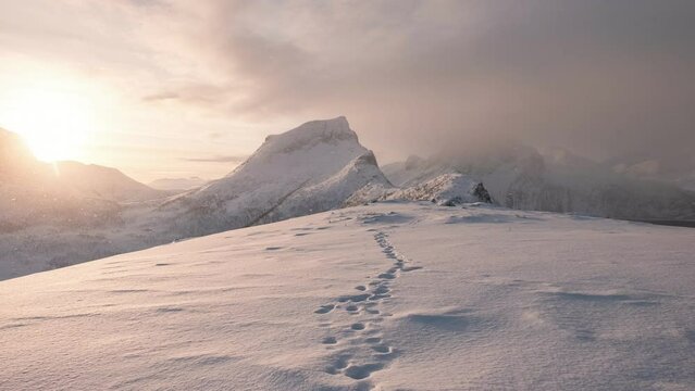 Sunrise over snowy mountain peak with footprint on winter in the morning at Segla mount, Senja island, Norway