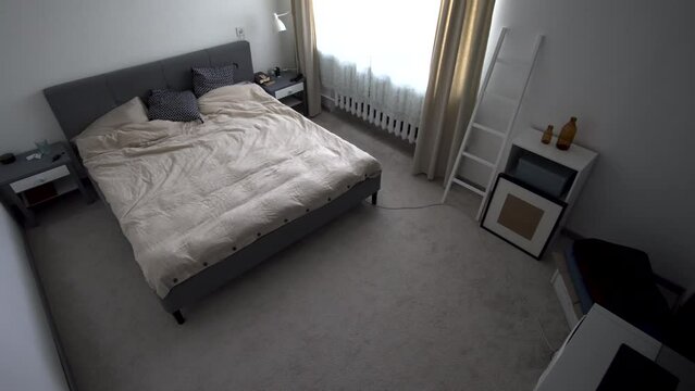 Home Interior of a modern, plain, minimal lived-in bedroom, with window, pan shot