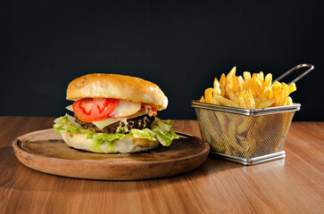 the photograph shows a delicious hamburger accompanied by french fries