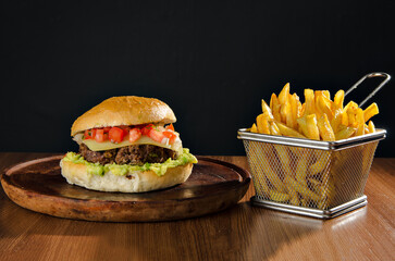 the photograph shows a delicious hamburger accompanied by french fries